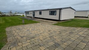 A mobile home with a paved driveway and a grassy lawn.