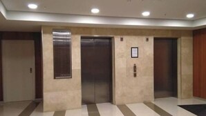 A hallway with three elevators, a sign on the wall, and a patterned floor. - Central CBD EXEC Stunning View Wifi Netflix Wine (Perth)