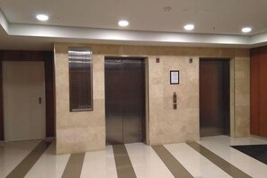A hallway with three elevators, a sign on the wall, and a patterned floor.