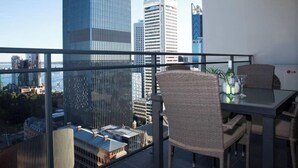 A balcony with a table and chairs, overlooking a cityscape with tall buildings. - Central CBD EXEC Stunning View Wifi Netflix Wine (Perth)