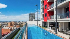 A rooftop swimming pool with a city view, a red building, and a tall structure in the background. - Central CBD EXEC Stunning View Wifi Netflix Wine (Perth)