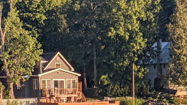 Une maison au bord du lac, dotée d’un quai, et entourée d’une forêt dense.