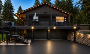 Eine Blockhütte mit überdachter Terrasse, zwei Garagentoren und einer Treppe, die zu einem oberen Stockwerk führt.