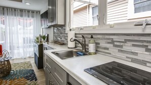 A modern kitchen with a built-in stove, a large window, and a tiled backsplash. - Riverside Tiny Home Retreat  (Hampton)