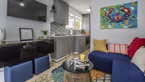A modern living room with a blue sofa, a black coffee table, and a TV mounted on the wall. - Riverside Tiny Home Retreat  (Hampton)