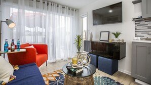 A modern living room with a red sofa, a black coffee table, and a TV mounted on the wall. - Riverside Tiny Home Retreat  (Hampton)