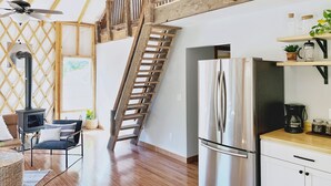 Una cocina moderna con un refrigerador de acero inoxidable, una escalera de madera y una zona superior con barandilla de madera.