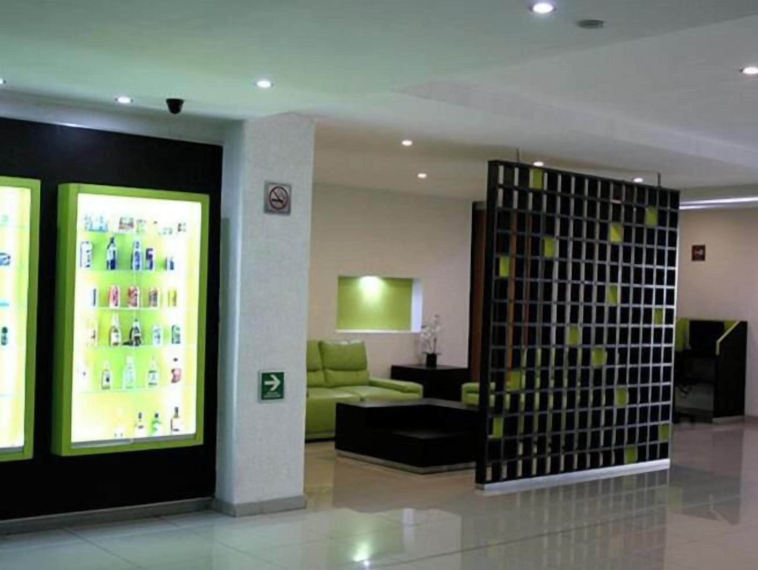 A reception area with a green sofa, a black partition, and a display of bottled water.