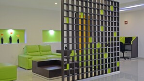 Ein modernes Interieur mit einem grünen Sofa, einer schwarzen Trennwand und einem Schreibtisch mit einem Computer.