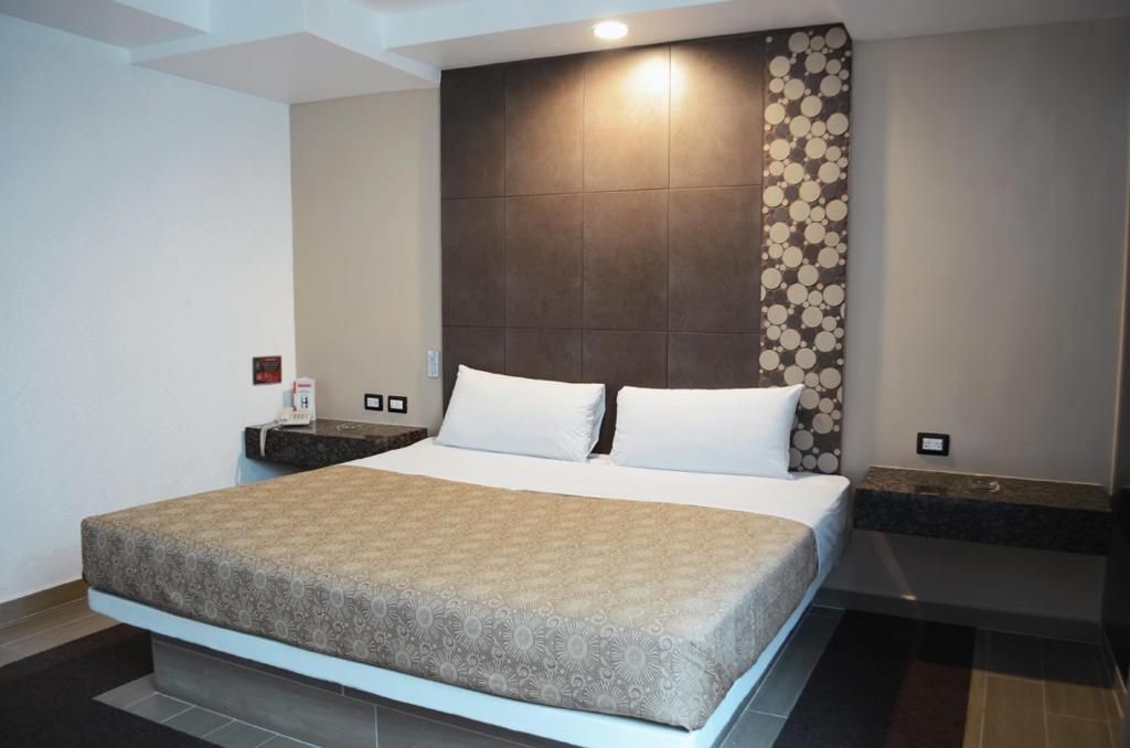 A modern hotel room with a large bed, a headboard with a circular pattern, and a nightstand with a phone and a small table.