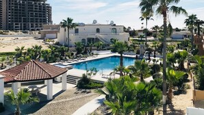 A resort with a swimming pool, palm trees, and a beach area. - Breathtaking Custom Home in Sandy Beach with Great Amenities! (Puerto Penasco)
