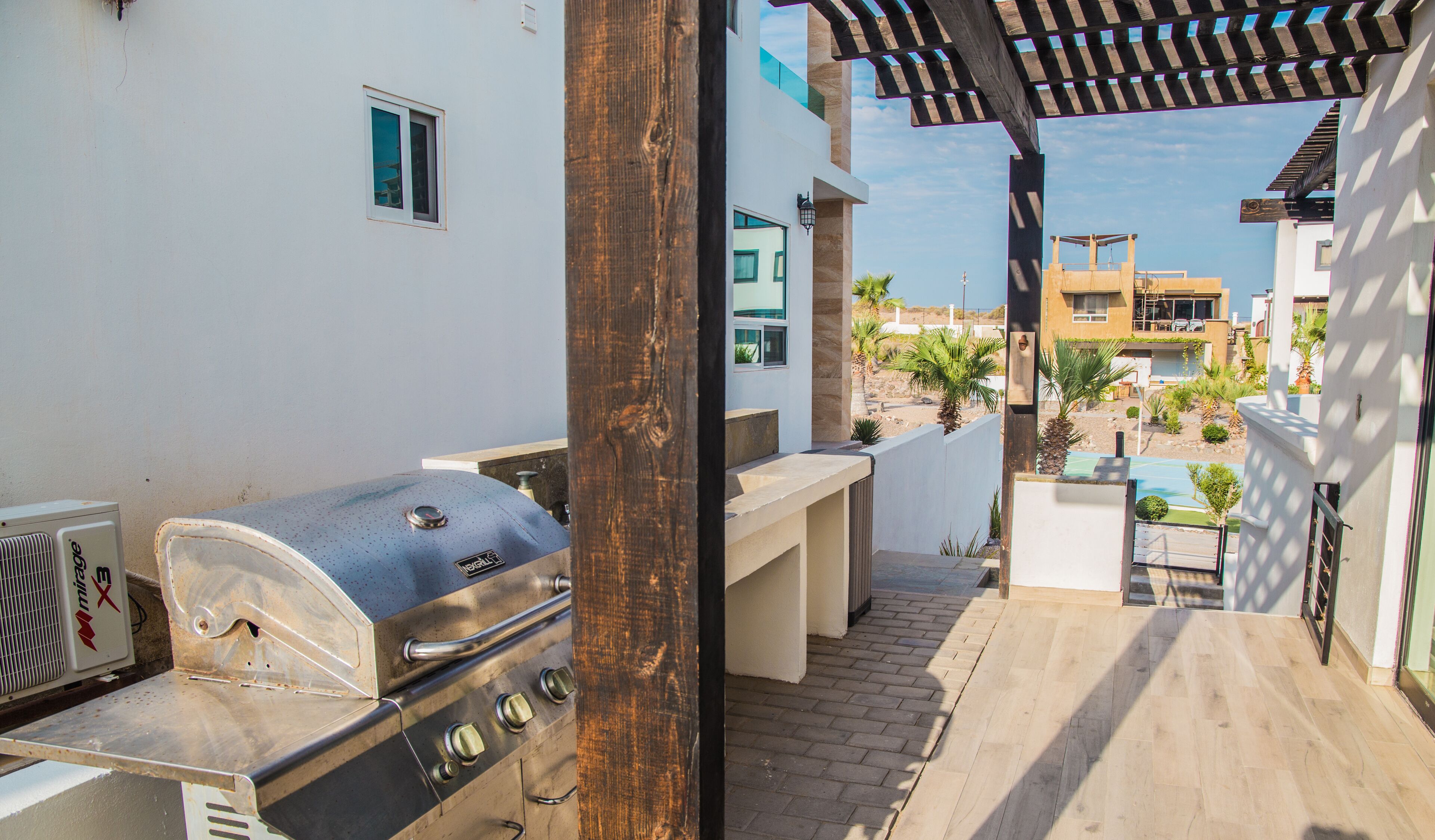 Un patio al aire libre con una parrilla, una mesa pequeña y una pérgola.