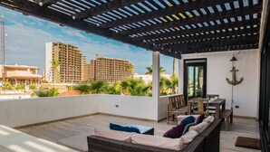 A covered outdoor seating area with a wicker sofa, a table, and chairs. - Breathtaking Custom Home in Sandy Beach with Great Amenities! (Puerto Penasco)