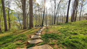 A stone pathway leading through a forested area with a lake in the background.