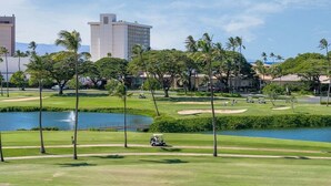 Un parcours de golf avec un plan d’eau, des palmiers et des bâtiments en arrière-plan.