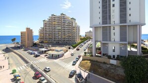 Ein Küstenort mit einer mehrstöckigen Hotelanlage, einem Parkplatz und einer Straße mit Fahrzeugen.