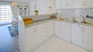 Eine moderne Küche mit weißen Schränken, einer Granit-Arbeitsplatte und einem eingebauten Geschirrspüler.