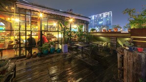 An outdoor seating area with wooden flooring, potted plants, and tables and chairs. - MinGuo Life Zhangjiajie (Zhangjiajie)