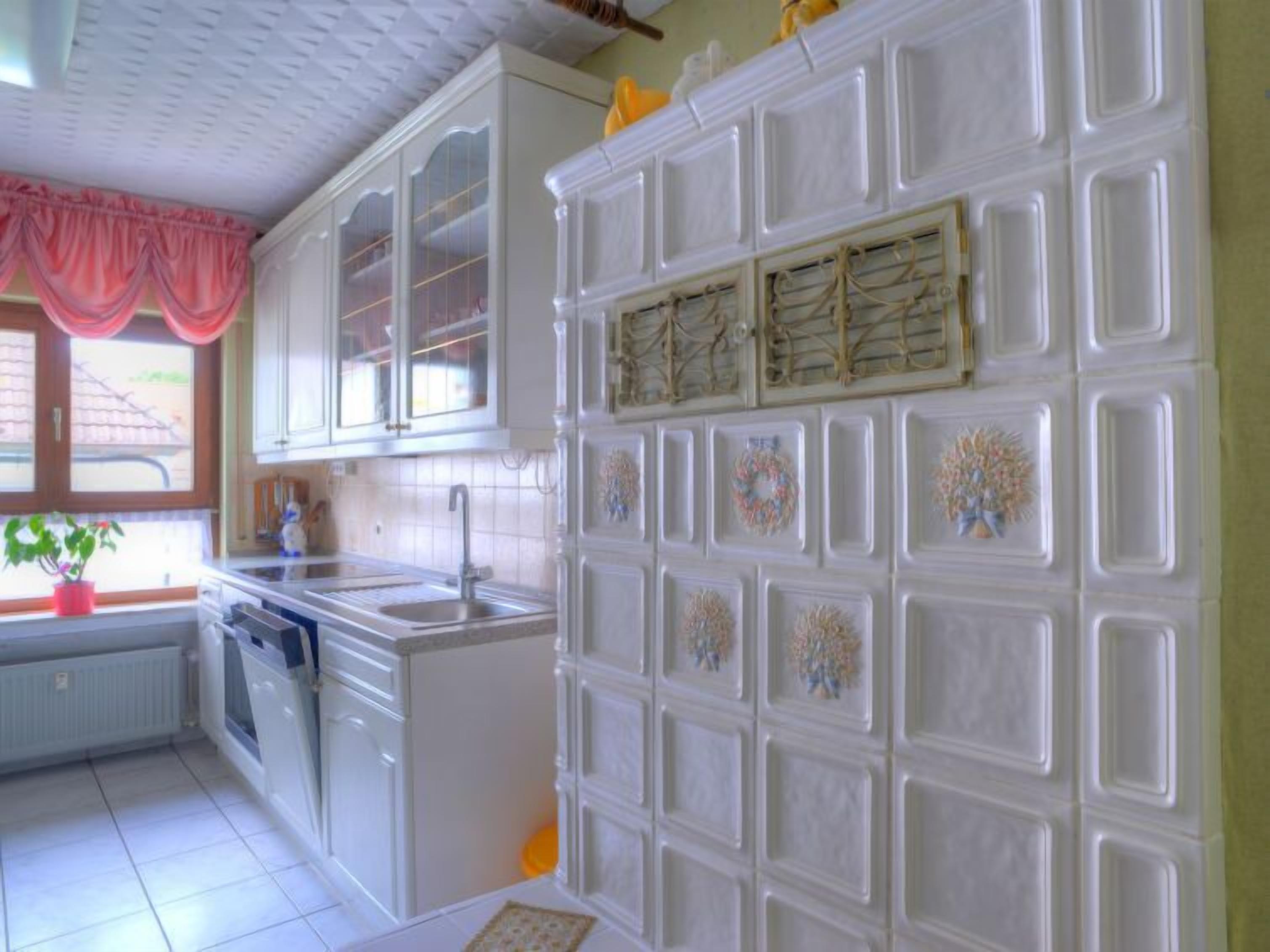 A kitchen with white cabinets, a sink, and decorative wall panels.