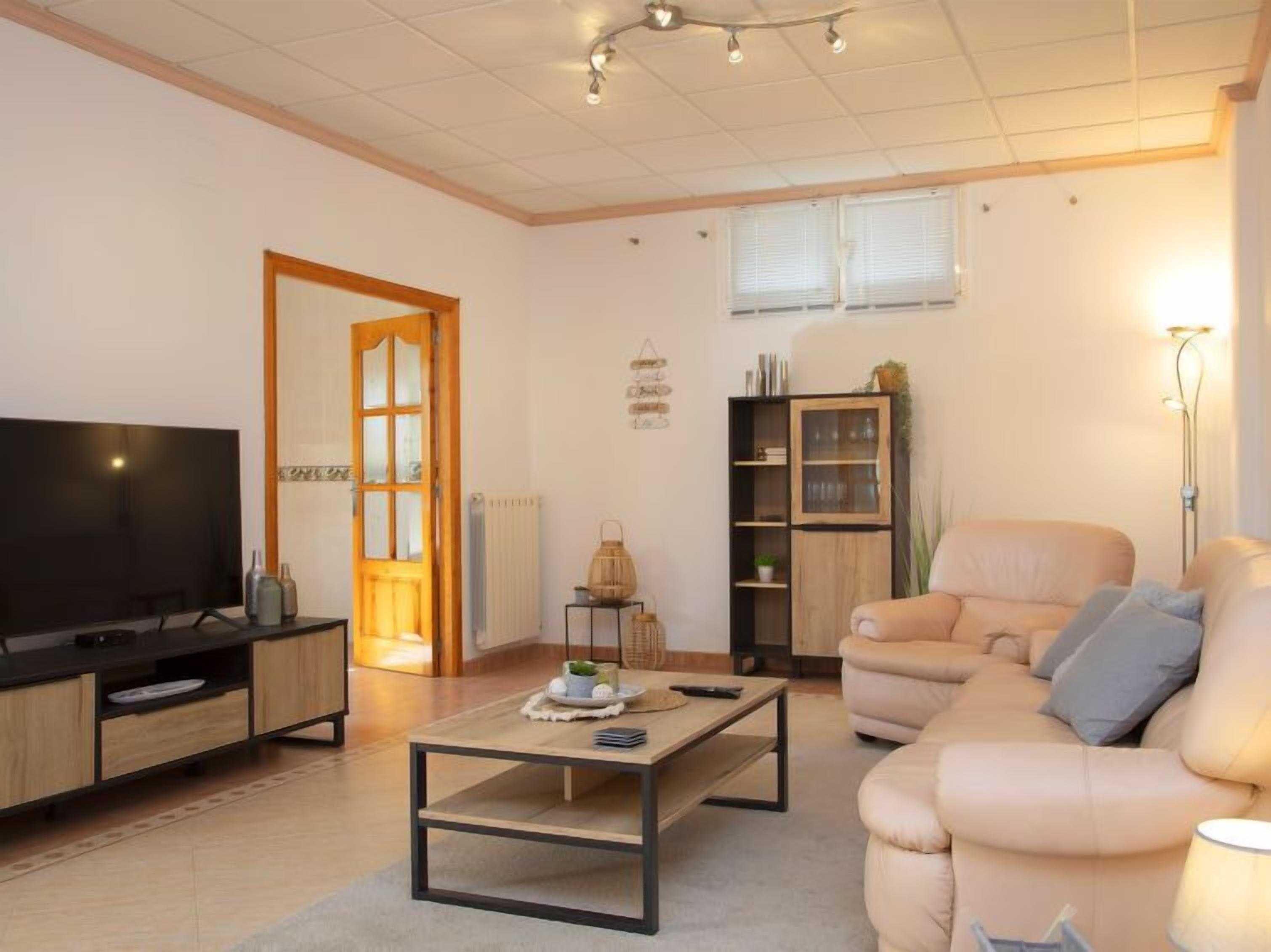 A modern living room with a sofa, a coffee table, a TV, and a bookshelf.