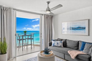 En moderne stue med balkon, loftventilator, en grå sofa og havudsigt.