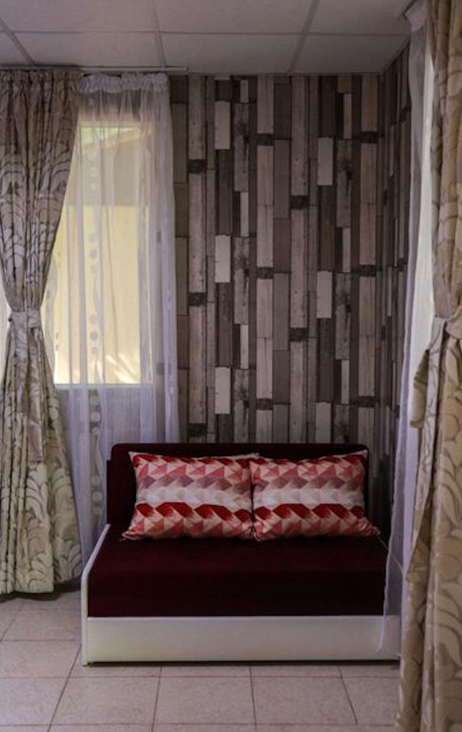 Une pièce avec un canapé, des rideaux et un mur décoré de motifs.