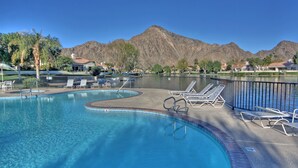 Une piscine avec des chaises longues et une vue sur les montagnes en arrière-plan.