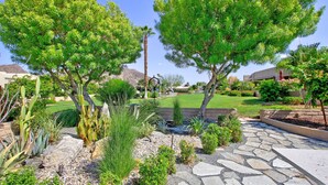 Un jardin aménagé avec différentes espèces de plantes et un sentier en pierre.