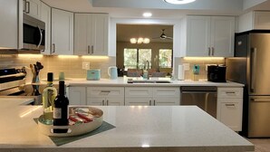 Een moderne keuken met witte kastjes, roestvrijstalen apparatuur en een centraal eiland met een schaal lekkernijen.