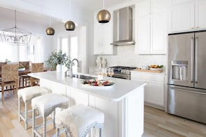 A modern kitchen with a central island, stainless steel appliances, and pendant lighting.
