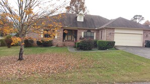 A two-story brick house with a garage, surrounded by a lawn and trees with autumn leaves. - Welcome to Polly's Place (Rockwell)