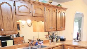 A kitchen with wooden cabinets, a stainless steel sink, and a dishwasher. - Welcome to Polly's Place (Rockwell)