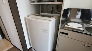 A compact kitchen with a built-in dishwasher, a stove, and a sink. - Sakuraya (Okinawa)