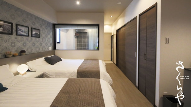A hotel room with two beds, a large window, a mirror, and a wardrobe. - Sakuraya (Okinawa)