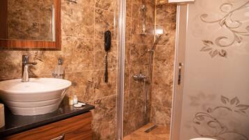 Un baño con lavamanos de mármol, cabina de ducha con paredes de vidrio y un inodoro.