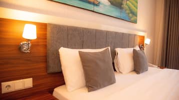 Habitación de hotel con una cama grande, dos lámparas de noche, cabecera de madera y un cuadro sobre la cama.