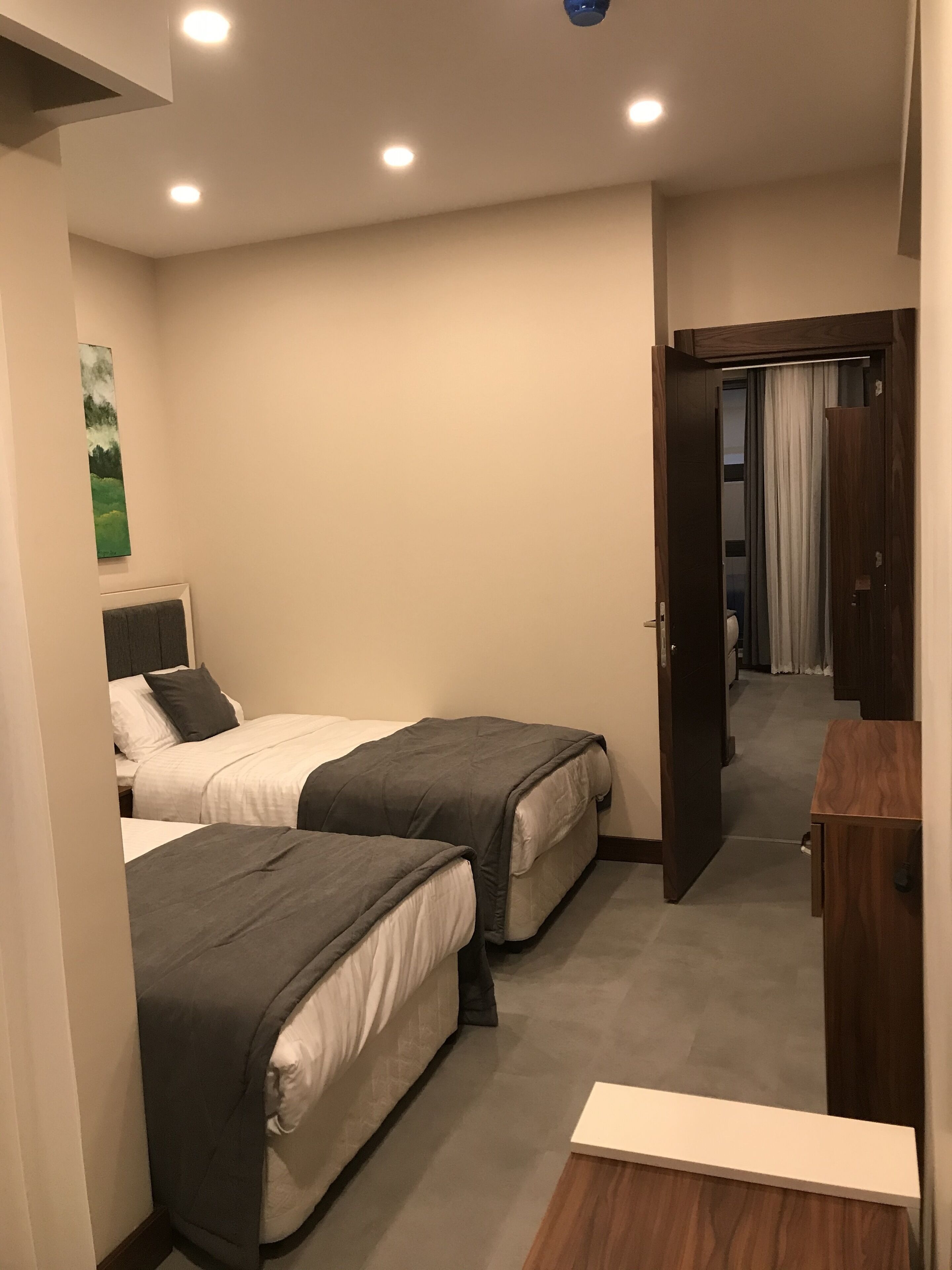 Una habitación de hotel con dos camas, un escritorio pequeño y un cuadro en la pared.