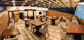 A restaurant with a curved ceiling, marble flooring, and a brick wall. Tables and chairs are arranged for dining. - Deryaman Hotel Trabzon (Trabzon)
