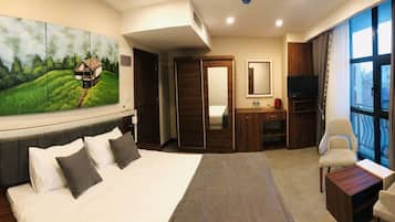 Habitación de hotel con una cama grande, un escritorio, una silla, un televisor y un cuadro en la pared.