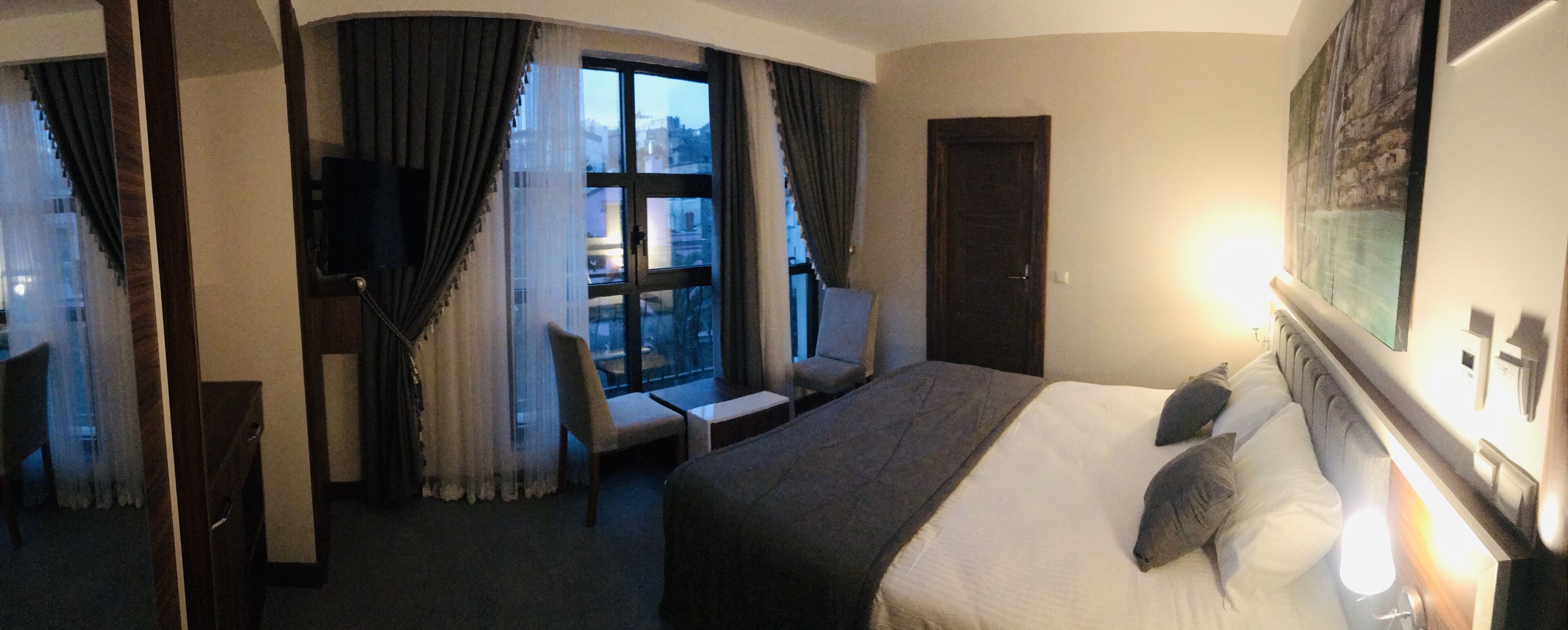 A hotel room with a large bed, a chair, a desk, and a TV.