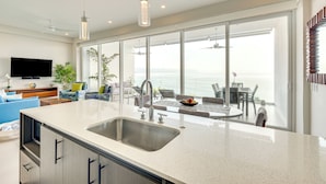 Cocina moderna con una isla grande, un lavaplatos integrado y un comedor con vista al mar.