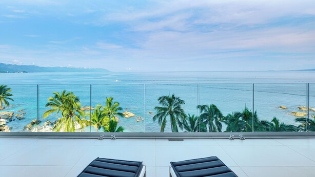 Un balcón con vista al mar y palmeras.