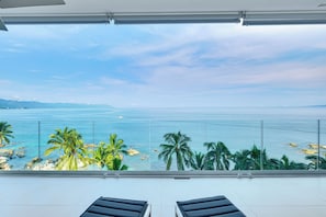 A balcony with a view of the sea and palm trees.
