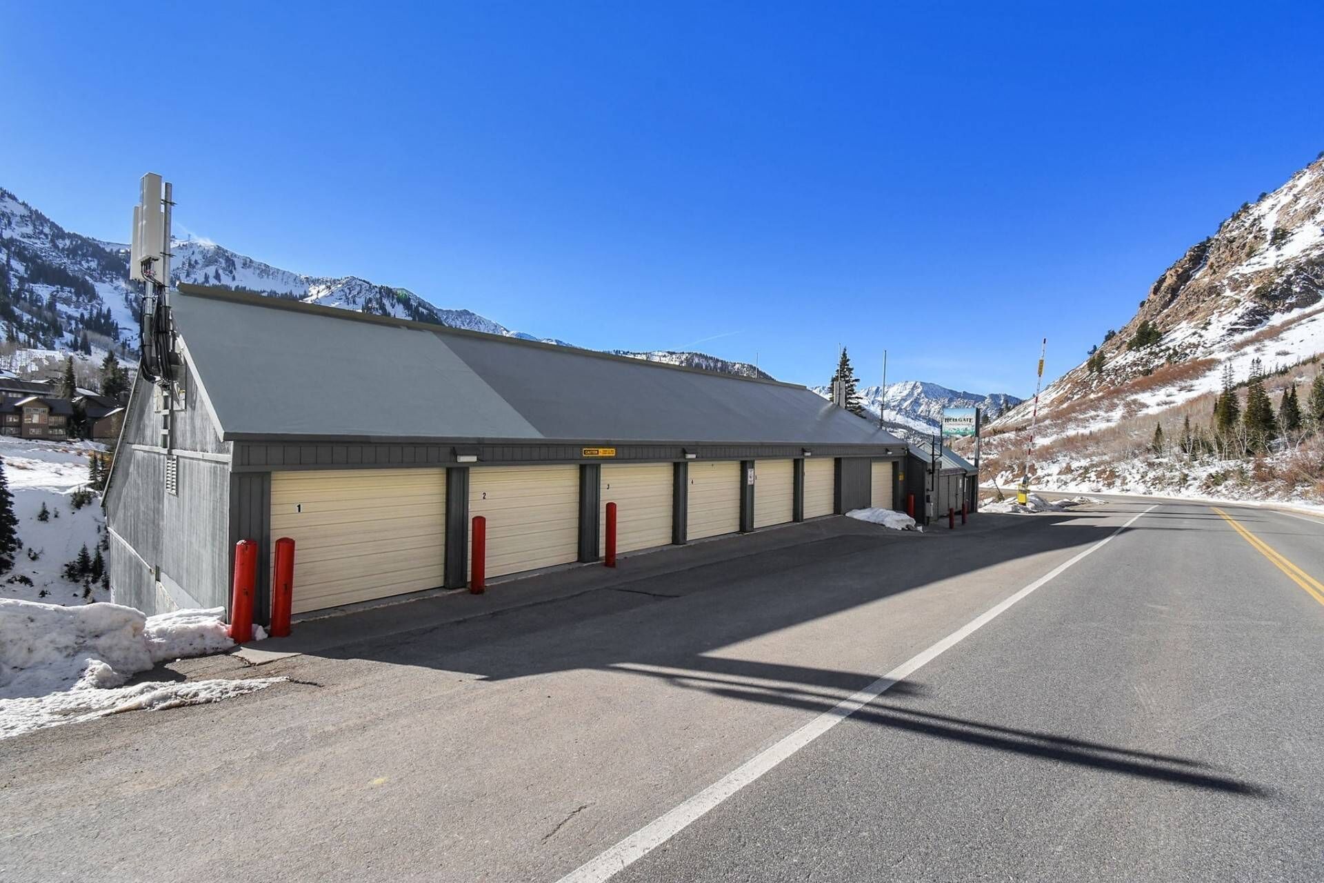 A building with a grey roof and beige garage doors, located beside a road with snow on the ground.