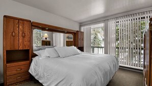A bedroom with a large bed, wooden wardrobe, and a window with blinds. - Great Weekend Destination-Between Snowbird & Alta, Hot Tub, BBQ, Free Parking, Free Ski Rental (Alta)
