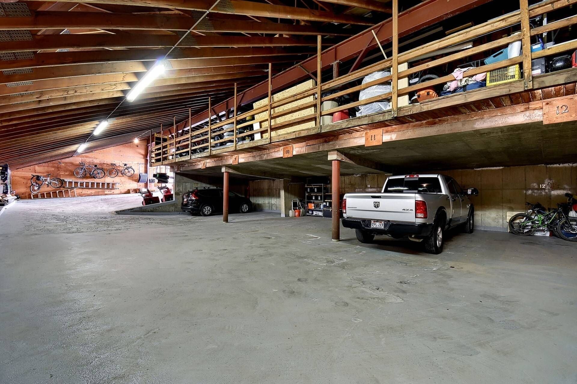 Un parking à plusieurs niveaux, avec un pick-up blanc garé au rez-de-chaussée.