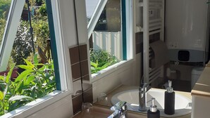A bathroom with a white sink, a mirror, and a window. - Chalet 100 m from the little sea of Gâvres (Riantec)