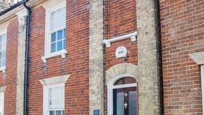 A red brick building with a black door and a white window. - Charming 3 bedroom cottage in heart of Southwold (Southwold)