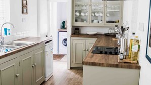 A modern kitchen with light wood cabinets, a central island, and a built-in oven. - Charming 3 bedroom cottage in heart of Southwold (Southwold)