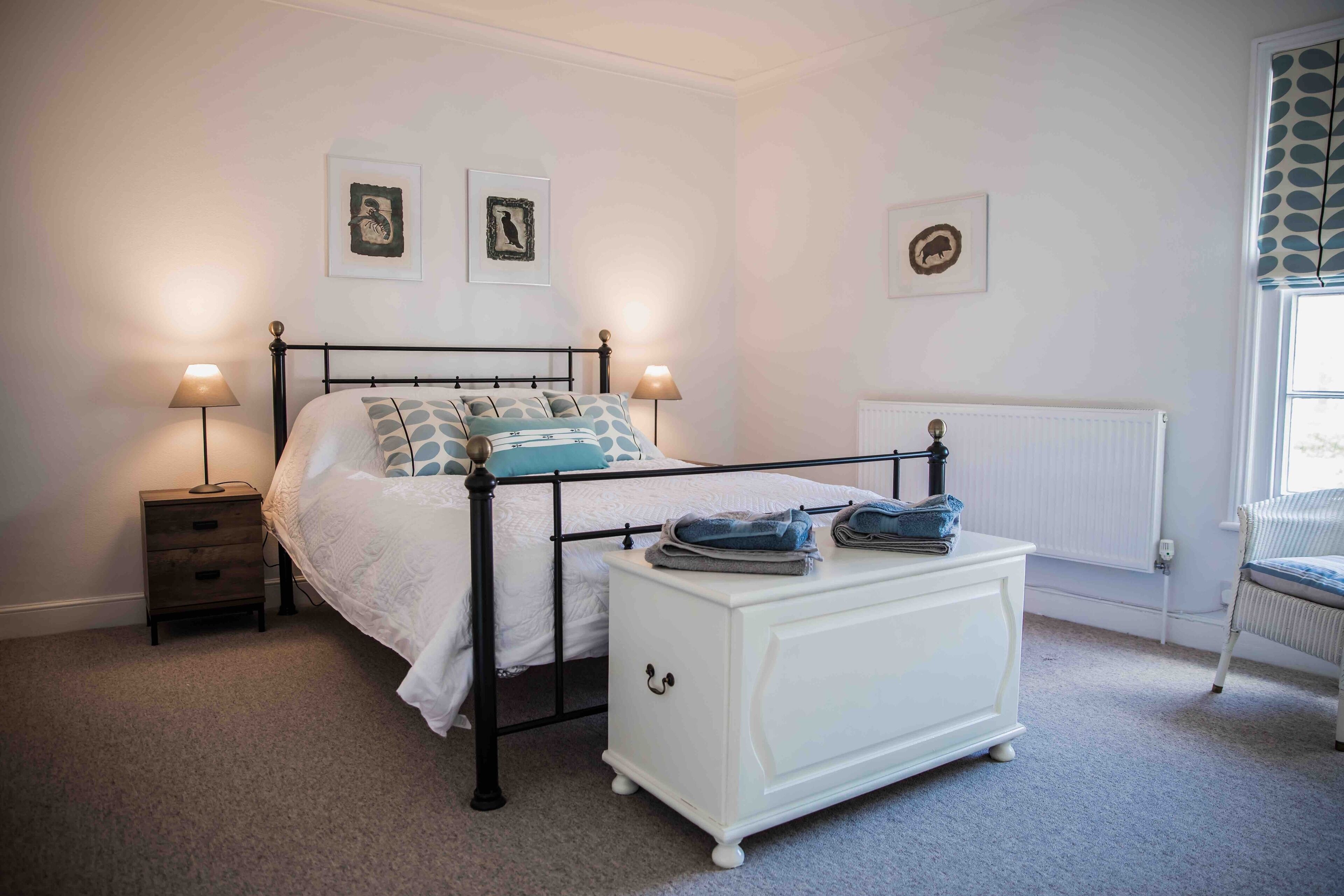 A bedroom with a bed, bedside tables, a dresser, and a radiator.